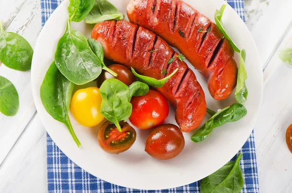 Gefrituurde worstjes met verse tomaten en spinazie — Stockfoto