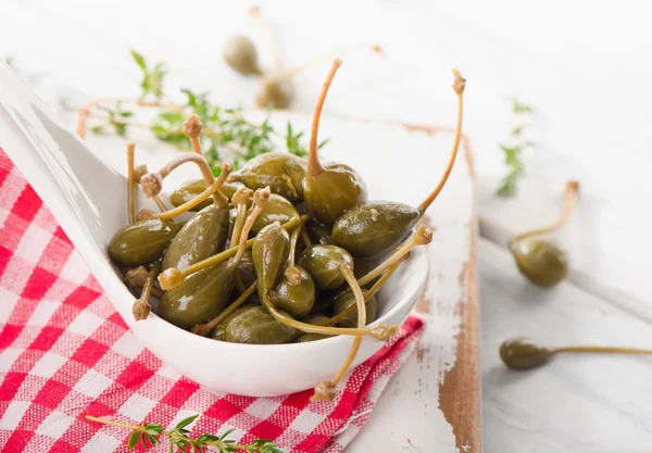 Capers in a white spoon. — Stock Photo, Image