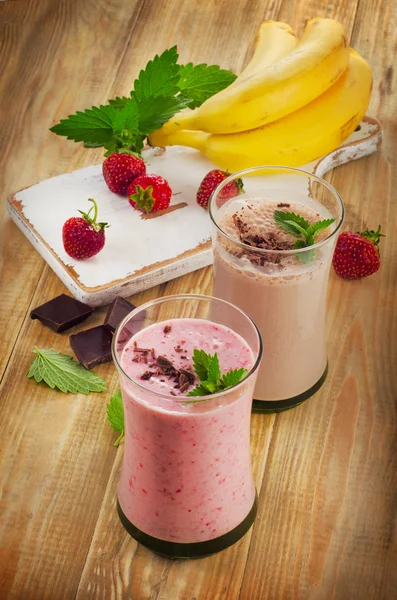 Smoothies com morango e banana em uma mesa de madeira . — Fotografia de Stock