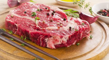 Ahşap masa üzerinde çiğ biftek.