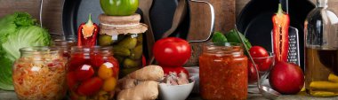 Ahşap bir arka planda cam kavanozlarda saklanmış sebzeler. Konserve yiyecek kavramı. Panorama.