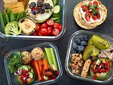 Çeşitli sağlıklı besleyici yemekleri olan beslenme çantaları. Sağlıklı abur cubur kavramı karanlık bir arka planda kutuda. Üst görünüm.