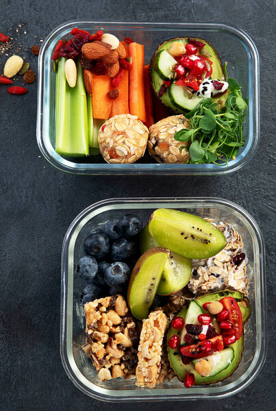 Lunchboxes with various healthy nutritious meals. Concept of healthy snacks in boxes on a dark background. Top view.