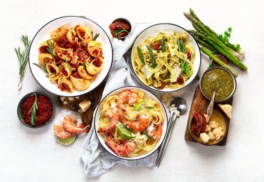 İtalyan makarnası. Etli domates soslu spagetti, deniz ürünleri makarnası, arka planda vejetaryen makarna. Üst görünüm.