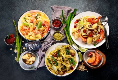 İtalyan makarnası. Etli domates soslu spagetti, deniz ürünleri makarnası, arka planda vejetaryen makarna. Üst görünüm.