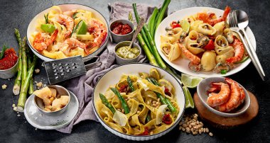 İtalyan makarnası. Etli domates soslu spagetti, deniz ürünleri makarnası, arka planda vejetaryen makarna. Üst görünüm.