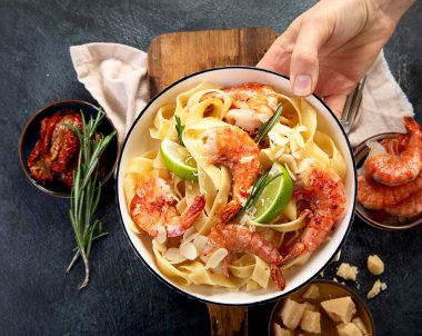 Koyu arkaplanda ev yapımı kremalı karidesli makarna. Üst görünüm.