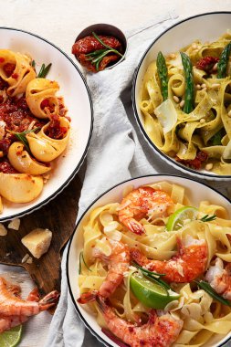 İtalyan makarnası. Etli domates soslu spagetti, deniz ürünleri makarnası, arka planda vejetaryen makarna. Üst görünüm.