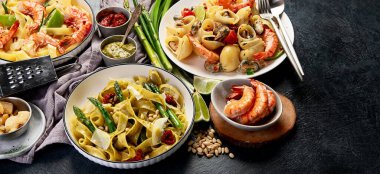 İtalyan makarnası. Etli domates soslu spagetti, deniz ürünleri makarnası, arka planda vejetaryen makarna. Üst görünüm.