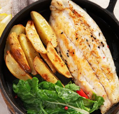 Balık tabağı - kızarmış morina balığı, kızarmış patates ve hafif arkaplanda salata ile morina filetosu. Üst görünüm.