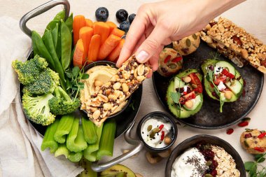 Çeşitli humus sosları. Sebzeli humus tabağı. Havuç, kereviz çubukları. Vejetaryen ve geleneksel humus hafif bir arka planda sağlıklı ve vejetaryen atıştırmalığı gibidir. Üst görünüm.