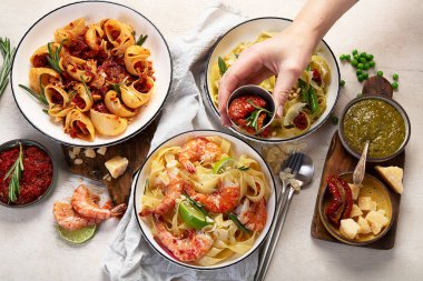 İtalyan makarnası. Etli domates soslu spagetti, deniz ürünleri makarnası, arka planda vejetaryen makarna. Üst görünüm.