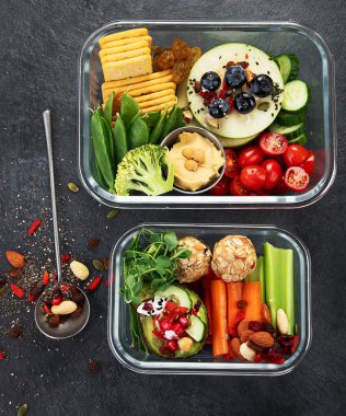 Çeşitli sağlıklı besleyici yemekleri olan beslenme çantaları. Sağlıklı abur cubur kavramı karanlık bir arka planda kutuda. Üst görünüm.