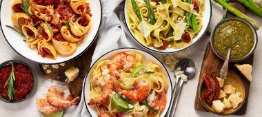 İtalyan makarnası. Etli domates soslu spagetti, deniz ürünleri makarnası, arka planda vejetaryen makarna. Üst görünüm.