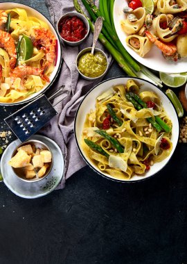 İtalyan makarnası. Etli domates soslu spagetti, deniz ürünleri makarnası, arka planda vejetaryen makarna. Üst görünüm.