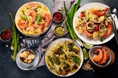 İtalyan makarnası. Etli domates soslu spagetti, deniz ürünleri makarnası, arka planda vejetaryen makarna. Üst görünüm.