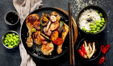 Tatlı ve tuzlu jöleli tavuk kanatları koyu arkaplanda pirinç ve mantarla servis edilir. Üst görünüm.