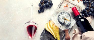 Kırmızı şarap ve aperatif. Şişeli şarap bardağı, parti için çeşitli aperatifler, arka planda kutlama. Üst Manzara. Kopyalama alanı olan Panorama