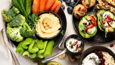 Çeşitli humus sosları. Sebzeli humus tabağı. Havuç, kereviz çubukları. Vejetaryen ve geleneksel humus hafif bir arka planda sağlıklı ve vejetaryen atıştırmalığı gibidir. Üst görünüm.