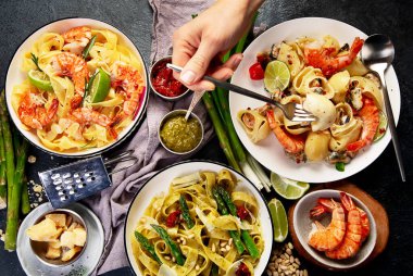 İtalyan makarnası. Etli domates soslu spagetti, deniz ürünleri makarnası, arka planda vejetaryen makarna. Üst görünüm.