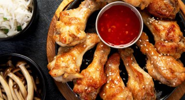 Koyu arkaplanda pilav ve mantarla servis edilen tavuk kanatları. Üst görünüm.