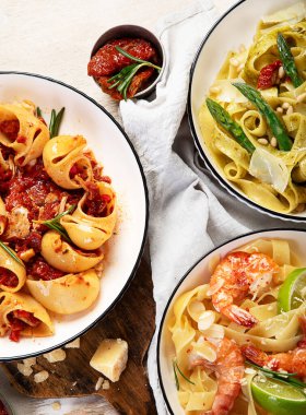 İtalyan makarnası. Etli domates soslu spagetti, deniz ürünleri makarnası, arka planda vejetaryen makarna. Üst görünüm.