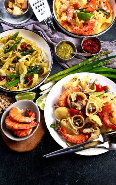 İtalyan makarnası. Etli domates soslu spagetti, deniz ürünleri makarnası, arka planda vejetaryen makarna. Üst görünüm.