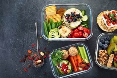 Çeşitli sağlıklı besleyici yemekleri olan beslenme çantaları. Sağlıklı abur cubur kavramı karanlık bir arka planda kutuda. Üst görünüm.