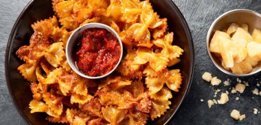 Ev yapımı Moda Makarna Cips. Koyu arkaplanda parmesanlı çıtır Baharatlı Pasta Farfalle. Üst görünüm.