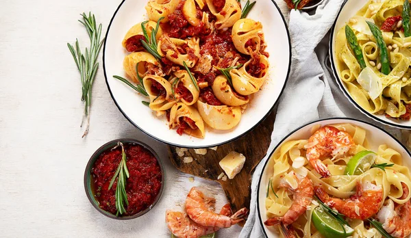 İtalyan makarnası. Etli domates soslu spagetti, deniz ürünleri makarnası, arka planda vejetaryen makarna. Üst görünüm.
