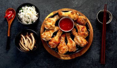 Koyu arkaplanda pilav ve mantarla servis edilen tavuk kanatları. Üst görünüm.