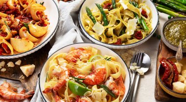 İtalyan makarnası. Etli domates soslu spagetti, deniz ürünleri makarnası, arka planda vejetaryen makarna. Üst görünüm.