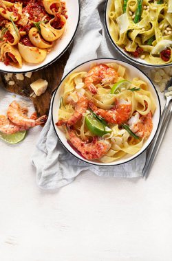 İtalyan makarnası. Etli domates soslu spagetti, deniz ürünleri makarnası, arka planda vejetaryen makarna. Üst görünüm.