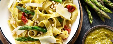 Fesleğenli ve çam fıstıklı makarna ve beyaz tabak. Geleneksel İtalyan tarifine göre koyu arkaplanda fituçin al pesto makarna. Üst Manzara. Panorama, banne