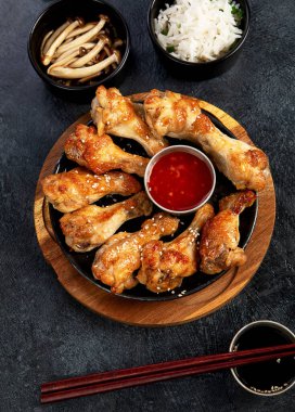 Koyu arkaplanda pilav ve mantarla servis edilen tavuk kanatları. Üst görünüm.