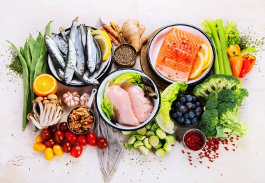 Hafif arka planda pek çok farklı sağlıklı yiyecek. Taze sebze, et, balık, tahıl ve meyve. Üst görünüm.