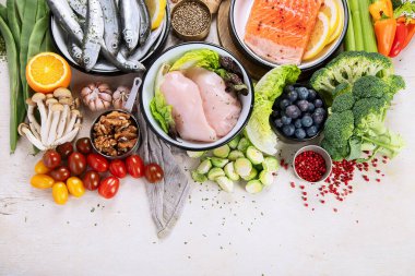 Hafif arka planda pek çok farklı sağlıklı yiyecek. Taze sebze, et, balık, tahıl ve meyve. Üst görünüm.