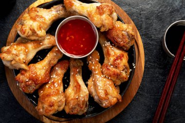 Koyu arkaplanda pilav ve mantarla servis edilen tavuk kanatları. Üst görünüm.