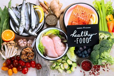 Hafif arka planda pek çok farklı sağlıklı yiyecek. Taze sebze, et, balık, tahıl ve meyve. Üst görünüm.