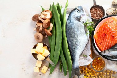Beyaz arka planda D vitamini bakımından zengin ürünlerle kompozisyon, üst manzara. Doğal D vitamini kaynakları (Balık, peynir, yumurta, mantar)