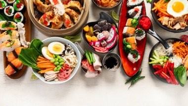 Hafif arka planda çeşitli Asya yemekleri içeren bir kompozisyon. Üst görünüm.