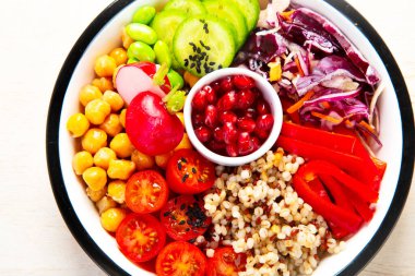 Sağlıklı sebzelerle vejetaryen yemeği ve arka planda meyve tabakları. Buda kasesi konsepti. Üst görünüm.