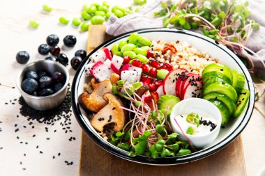 Sağlıklı sebzelerle vejetaryen yemeği ve arka planda meyve tabakları. Buda kasesi konsepti. Üst görünüm.