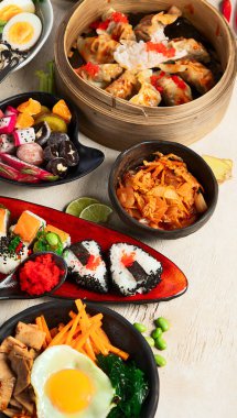 Hafif arka planda çeşitli Asya yemekleri içeren bir kompozisyon. Üst görünüm.