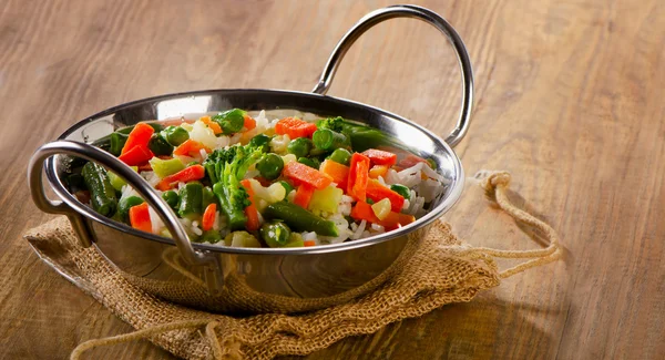 Arroz com legumes em um fundo de madeira . — Fotografia de Stock