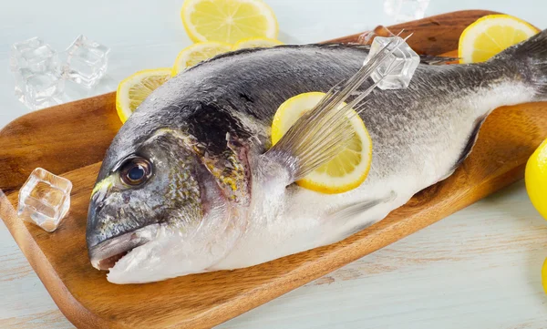 Dorado crudo con limón en una tabla de cortar —  Fotos de Stock