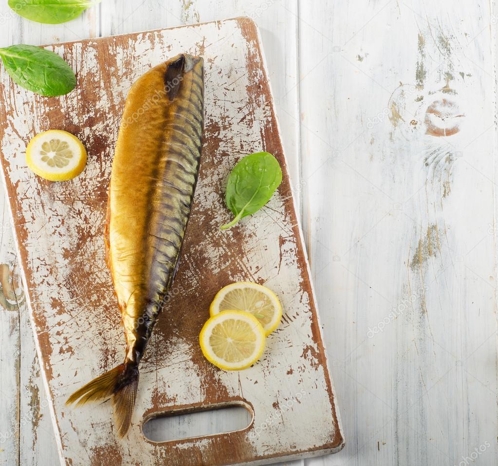 Smoked fish on old white wooden board.