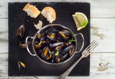 Karanlık bir arka plan üzerine bir tabak haşlanmış midye.