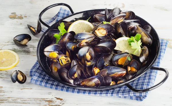 Copper pot of mussels garnished with lemon slices. — Stock Photo, Image