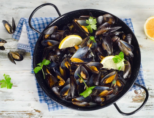 Koperen pot van gastronomische mosselen geserveerd op een servet gegarneerd met — Stockfoto